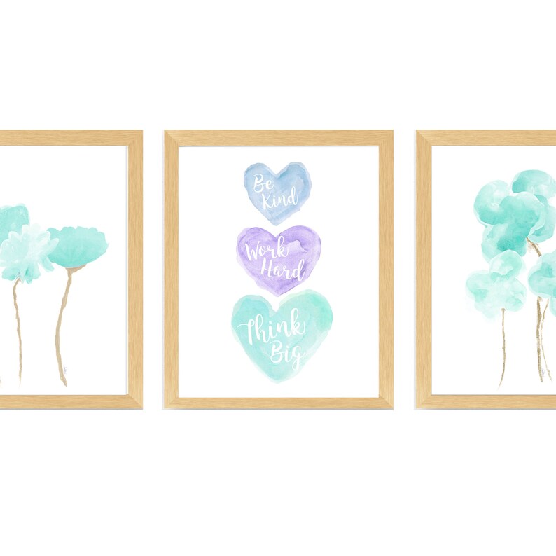 May include: Three framed watercolor prints with inspirational messages. The center print features three stacked hearts with the words "Be Kind", "Work Hard", and "Think Big". The left print features two light blue watercolor flowers. The right print features three light blue watercolor flowers.