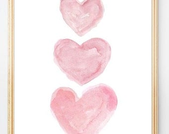 Peut inclure: Une œuvre d'art murale encadrée représentant trois cœurs à l'aquarelle alignés verticalement dans des tons de rose tendre. Les cœurs présentent des coups de pinceau visibles et des dégradés, sur fond blanc dans un cadre doré fin.