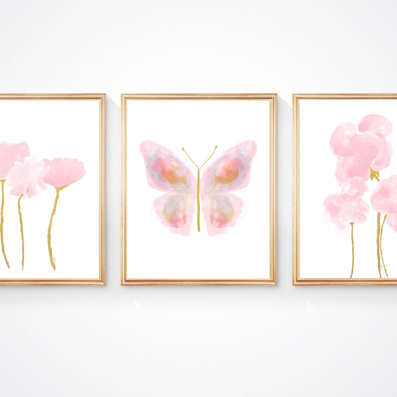 May include: Set of three watercolor prints featuring pink flowers and a butterfly with gold accents. The prints are framed in gold.