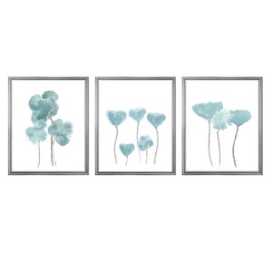 Pu&ograve; includere: Set di tre stampe ad acquerello incorniciate con fiori blu astratti. Le stampe sono in cornici argentate e hanno uno sfondo bianco.