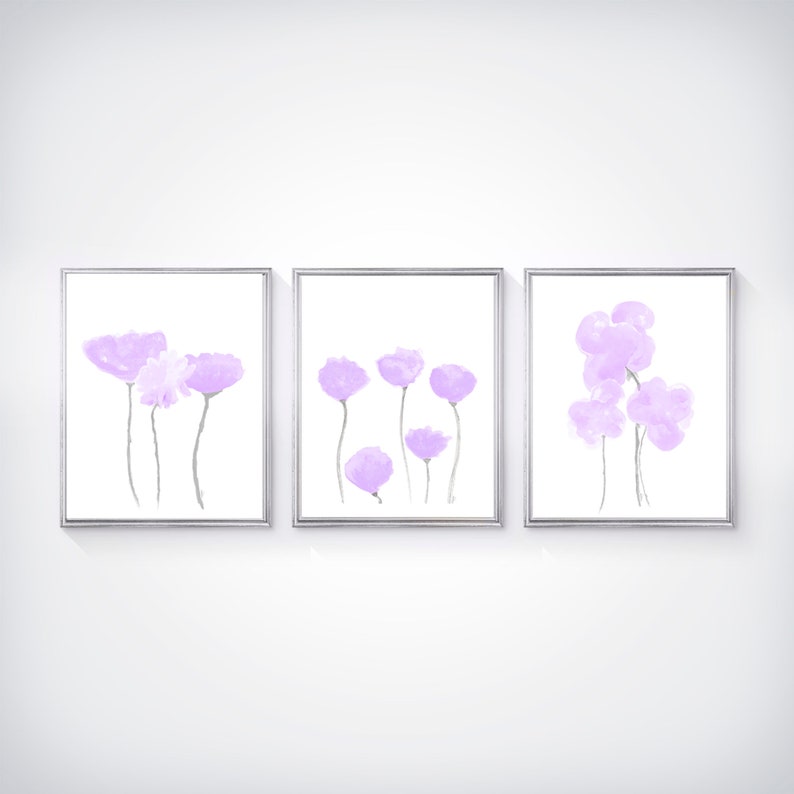 Pu&ograve; includere: Set di tre stampe incorniciate con dipinti astratti ad acquerello di fiori viola. Le stampe sono in semplici cornici argentate e hanno uno sfondo bianco.