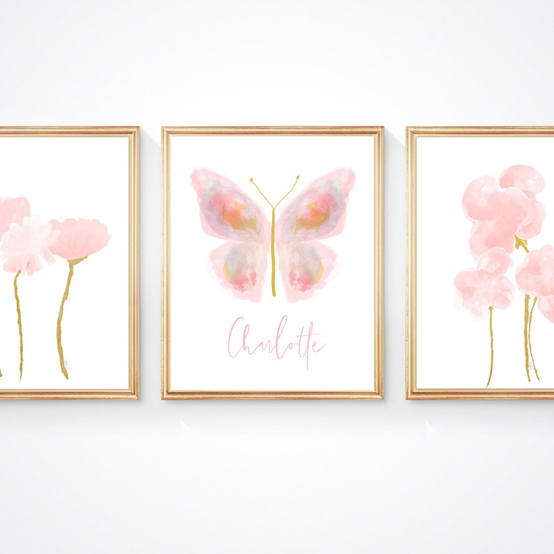 May include: Three framed prints with watercolor illustrations of pink flowers and a butterfly. The center print features the name "Charlotte".