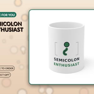 May include: A white ceramic mug featuring a graphic of a green semicolon enclosed in brackets. Below the graphic, the text reads SEMICOLON ENTHUSIAST in black and green lettering. The mug has a cylindrical shape and a smooth, clean finish.