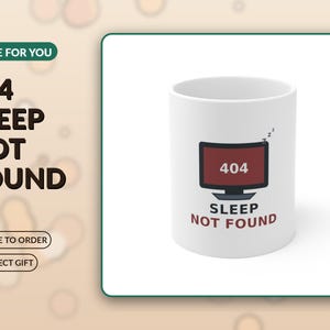 Puede incluir: Una taza de cerámica blanca con un gráfico de un monitor de computadora que muestra el texto 404 y las palabras SLEEP NOT FOUND debajo. El gráfico del monitor es de color rojo oscuro con un marco negro y símbolos zzz sobre la pantalla.