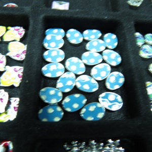 May include: A collection of small, blue and white polka dot patterned ceramic tiles. The tiles are arranged in a grid pattern and are all the same size.