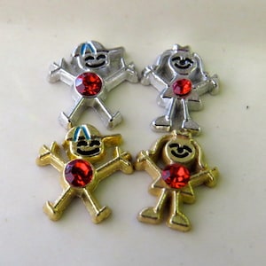 May include: Four small metal charms in the shape of stick figures. Two charms are silver and two are gold. Each charm has a red rhinestone in the center.