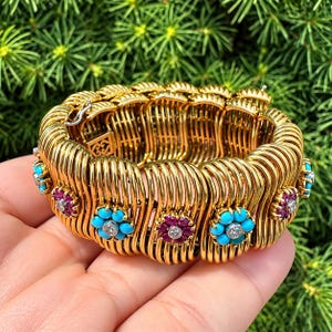 Pulseira rígida em ouro amarelo 18K com turquesa, rubi e diamantes em formato de cluster.