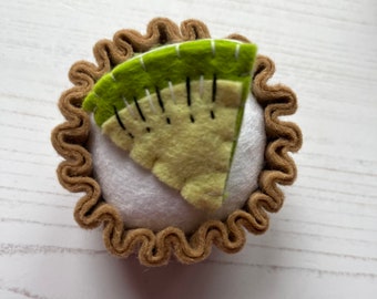 Può includere: Una torta di kiwi in feltro con una crosta marrone e un ripieno di kiwi verde e giallo.