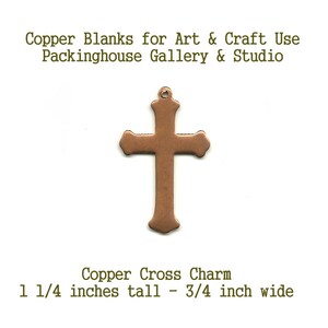 May include: A copper cross charm with a small loop at the top. The text reads: Copper Blanks for Art & Craft Use, Packinghouse Gallery & Studio, Copper Cross Charm, 1 1/4 inches tall - 3/4 inch wide. The cross has a smooth, metallic finish.
