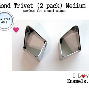 May include: Two silver-colored metal diamond-shaped trivets. The text reads: Diamond Trivet (2 pack) Medium size, New Item 2021, and I Love Enamels.com. The design features a magnifying glass icon and a small pink heart icon.