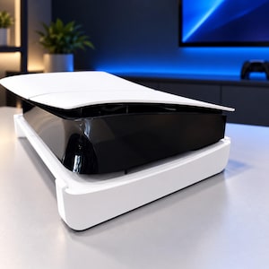 Op de afbeelding: Een spelcomputer met een strak, tweekleurig ontwerp met een glanzend zwart middengedeelte tussen twee gebogen, matwitte zijpanelen. De console is horizontaal geplaatst en toont een moderne, aerodynamische uitstraling.