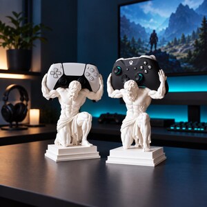 Puede incluir: Dos estatuas blancas de una figura arrodillada con complexión musculosa, cada una montada sobre una base cuadrada. Una figura sostiene un mando de videojuego blanco sobre su cabeza, mientras la otra sostiene un mando negro.