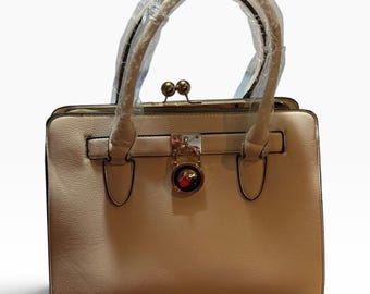 Nova bolsa satchel estruturada bege com ferragens douradas e alça superior/de ombro.