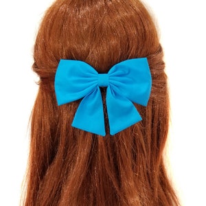May include: A bright blue bow hair clip. The bow is made of a soft, satin-like fabric and is tied in a classic bow shape.