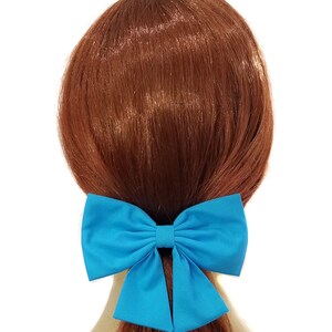 May include: A large turquoise blue fabric bow hair clip. The bow is tied in a large, full loop with two tails.