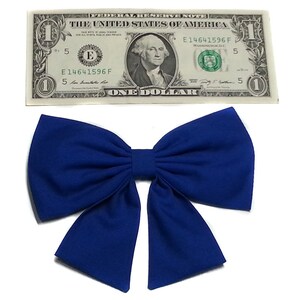 May include: A large, royal blue bow made of fabric. The bow is tied in a classic style with two loops and a center knot.