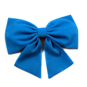 May include: A large, bright blue bow made of fabric. The bow is tied in a classic style with two long tails.