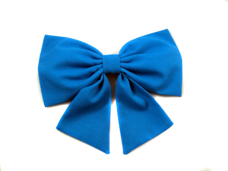 May include: A large, bright blue bow made of fabric. The bow is tied in a classic style with two long tails.