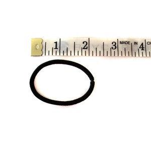 May include: A black hair elastic measuring approximately 2 inches in diameter, next to a white tape measure marked with inches.
