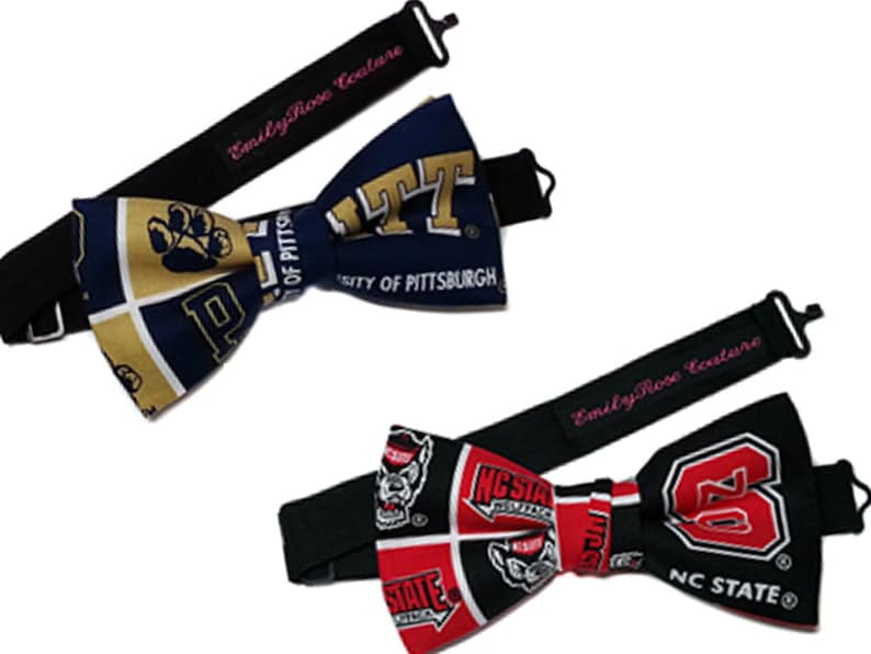 May include: Two bow ties with adjustable straps. The first bow tie is navy blue and gold with the University of Pittsburgh logo and mascot. The second bow tie is black and red with the NC State Wolfpack logo. Both bow ties have the text "Emily Rose Couture" on the strap.