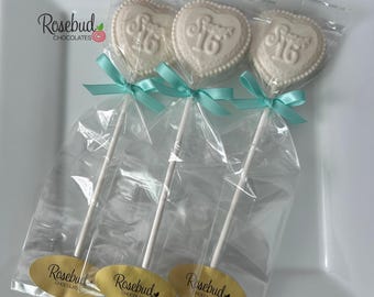 May include: Three white heart-shaped chocolate lollipops, each embossed with the text Sweet 16. Each lollipop is individually wrapped in clear plastic, tied with a light blue ribbon, and features a gold oval sticker labeled Rosebud Chocolates.