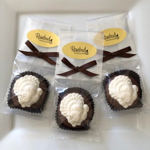 May include: Three individually wrapped chocolate turkeys in clear cellophane bags tied with brown ribbon. Each bag has a gold oval sticker with the text "Rosebud Chocolates".