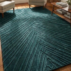 May include: A large rectangular area rug in a deep teal color featuring a raised, textured chevron pattern. The rug has a dense, plush pile with varying line thicknesses that create a geometric, directional design across the entire surface.