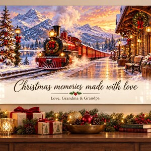 Könnte beinhalten: Ein rechteckiger Wanddruck mit einem Dampfzug an einem verschneiten Bahnhof vor einer Bergkulisse. Der Text lautet, Christmas memories made with love, Love, Grandma & Grandpa, mit einem kleinen Stechpalmen-Symbol darunter.