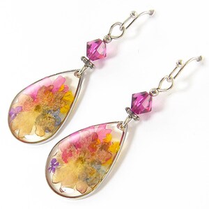 Colorful flower earrings feature real pressed, dried flowers in a clear resin teardrop. These pink and yellow multi-color earrings have a magenta Swarovski crystal bead accent. Lovely as spring or summer dangle earrings or any time of the year.