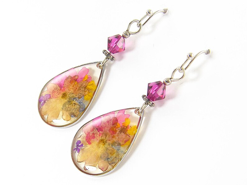 Colorful flower earrings feature real pressed, dried flowers in a clear resin teardrop. These pink and yellow multi-color earrings have a magenta Swarovski crystal bead accent. Lovely as spring or summer dangle earrings or any time of the year.