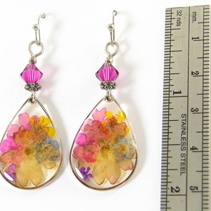 Colorful flower earrings feature real pressed, dried flowers in a clear resin teardrop. These pink and yellow multi-color earrings have a magenta Swarovski crystal bead accent. Lovely as spring or summer dangle earrings or any time of the year.
