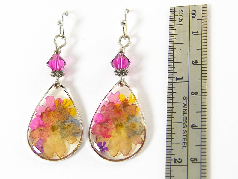 Colorful flower earrings feature real pressed, dried flowers in a clear resin teardrop. These pink and yellow multi-color earrings have a magenta Swarovski crystal bead accent. Lovely as spring or summer dangle earrings or any time of the year.