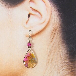 Colorful flower earrings feature real pressed, dried flowers in a clear resin teardrop. These pink and yellow multi-color earrings have a magenta Swarovski crystal bead accent. Lovely as spring or summer dangle earrings or any time of the year.