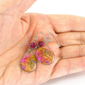 Colorful flower earrings feature real pressed, dried flowers in a clear resin teardrop. These pink and yellow multi-color earrings have a magenta Swarovski crystal bead accent. Lovely as spring or summer dangle earrings or any time of the year.