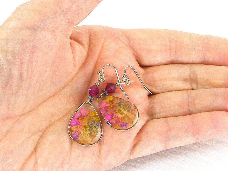 Colorful flower earrings feature real pressed, dried flowers in a clear resin teardrop. These pink and yellow multi-color earrings have a magenta Swarovski crystal bead accent. Lovely as spring or summer dangle earrings or any time of the year.