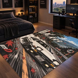 May include: A rectangular area rug featuring a graphic illustration of a white and black sports car drifting on a mountain road. The design includes red maple leaves, Japanese text, and a mountain landscape in the background. The car has a license plate reading 13-954.