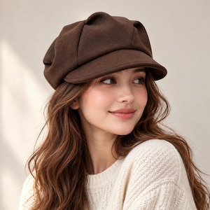 May include: A dark brown newsboy cap featuring a soft, felt-like texture with a rounded, multi-paneled crown and a short, stiff brim. The hat has a structured yet slouchy silhouette, providing a classic look with a solid, uniform color throughout.