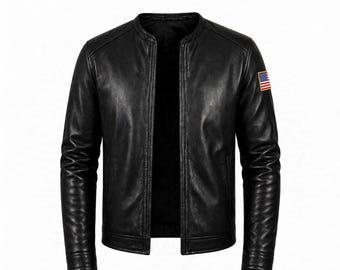 Könnte beinhalten: Eine schwarze Lederjacke mit Stehkragen, langen Ärmeln und einem kleinen rechteckigen Aufnäher der Flagge der Vereinigten Staaten am linken Oberarm. Die Jacke hat eine glatte Textur, eine Vorderöffnung und abgesteppte Details an den Ärmelbündchen.