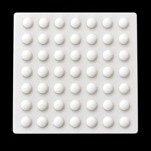 May include: A square white tactile paving tile featuring a grid of forty-nine raised, smooth, hemispherical domes arranged in seven rows and seven columns. The surface is uniform in color and texture, designed with a consistent pattern of bumps.
