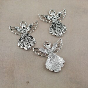 Pu&ograve; includere: Tre ciondoli a forma di angelo in argento con disegni intricati. Gli angeli hanno le ali e indossano abiti. I ciondoli sono perfetti per la creazione di gioielli o lo scrapbooking.