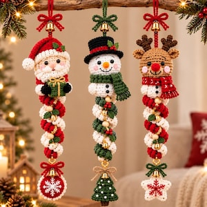 May include: Three hanging crochet Christmas ornaments featuring a Santa Claus, a snowman, and a reindeer. Each figure is attached to a long, spiraling red and white or green and white cord adorned with small gold bells and wooden beads.