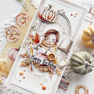 Op de afbeelding: Een handgemaakte kaart met een herfstthema met een meisje dat een boek leest met pompoenen, bladeren en de woorden "Happy Birthday".