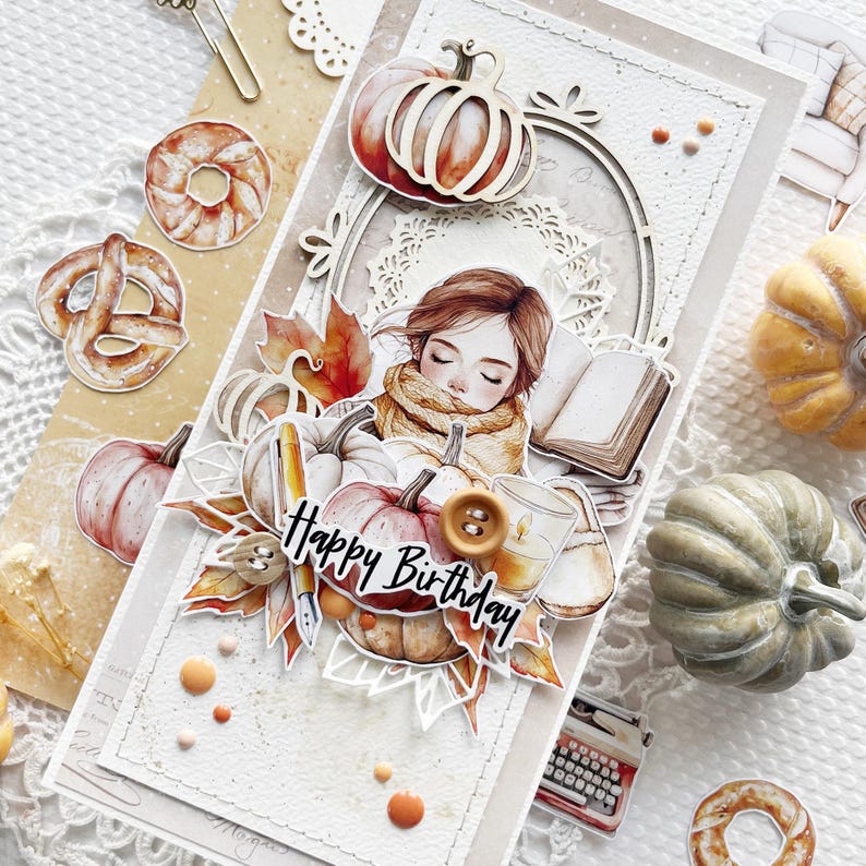 Op de afbeelding: Een handgemaakte kaart met een herfstthema met een meisje dat een boek leest met pompoenen, bladeren en de woorden "Happy Birthday".