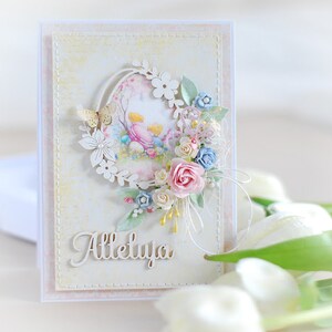 May include: A white card with a pastel floral design and the word "Alleluia" in a decorative font. The card features a wreath of flowers and a butterfly.
