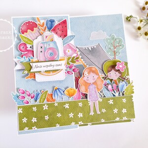 May include: A colorful card with a blue background and a green border. The card features a watercolor illustration of two girls camping with a tent, a camera, and flowers. The text on the card reads "Nasz wsp&oacute;lny czas".