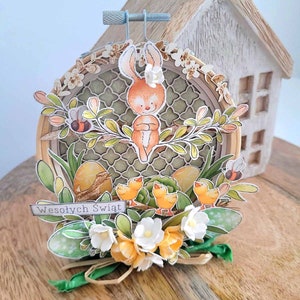 May include: A handmade Easter craft featuring a brown bunny rabbit sitting on a branch with green leaves and yellow flowers. The bunny is surrounded by yellow chicks and a sign that reads "Wesołych Świąt" which is Polish for "Happy Holidays".