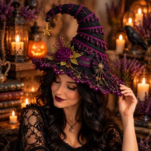 May include: A black crocheted witch hat featuring a pointed, curved top adorned with purple beads and a dangling gold star charm. The brim is decorated with a large purple crocheted rose, green leaves, and intricate gold-toned metal accents.
