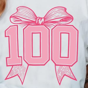 Pode incluir: Uma camiseta branca com um laço rosa e o número 100 em uma fonte rosa, com contorno. A camiseta é um download digital.