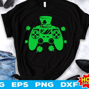 May include: Black t-shirt with a green video game controller design. The controller has a green shamrock on top and is surrounded by shamrocks. The text "HOBO CREATIONS" is in a red and white box in the lower right corner.