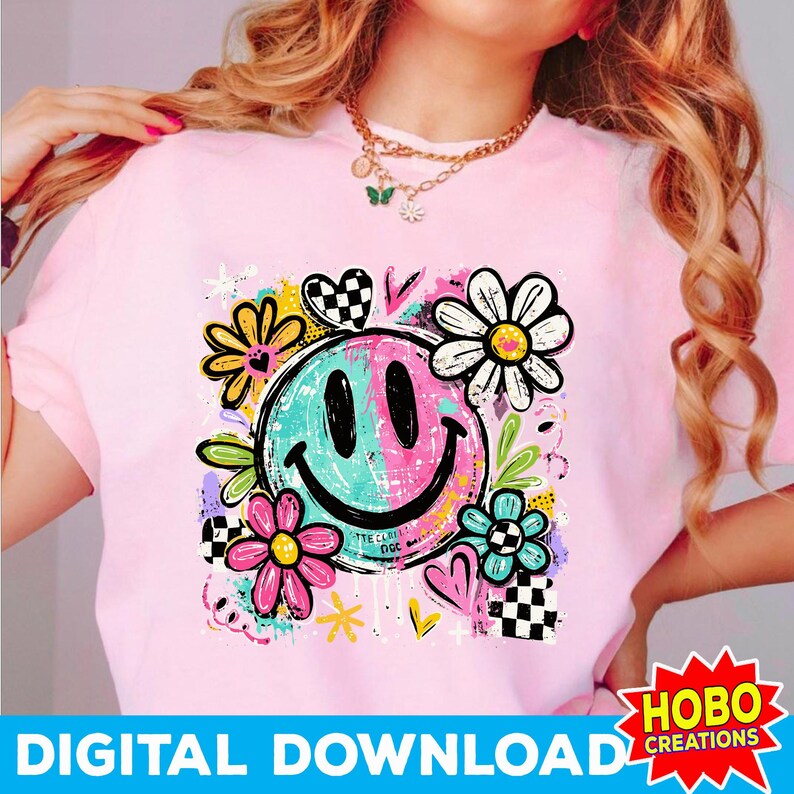 May include: Pink t-shirt featuring a colorful smiley face design with flowers, hearts, and the text "DIGITAL DOWNLOAD". The smiley face is split into teal and pink halves. The shirt has a crew neck.